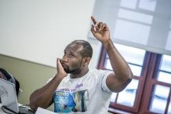 Photo of student raising hand in classroom.